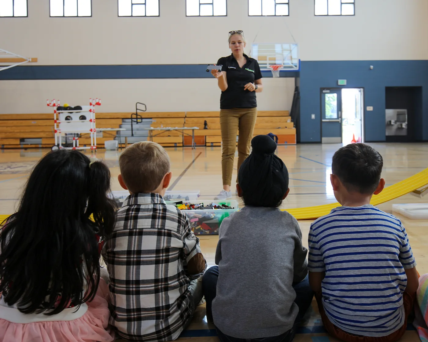 A BrainStorm instructor guiding students through a hands-on robotics lesson in a school gym.