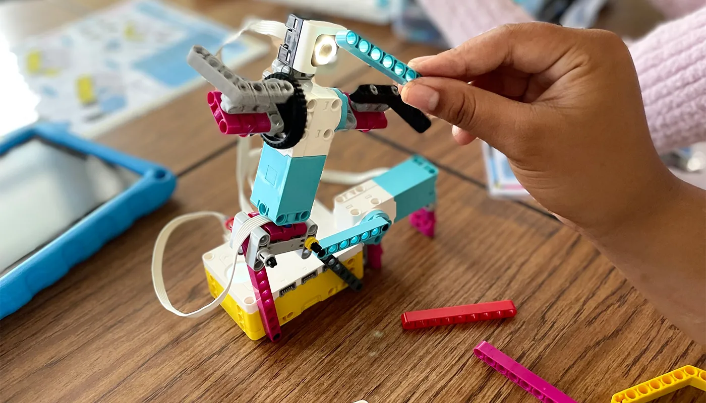 A student working closely with a colorful robotics mechanism.