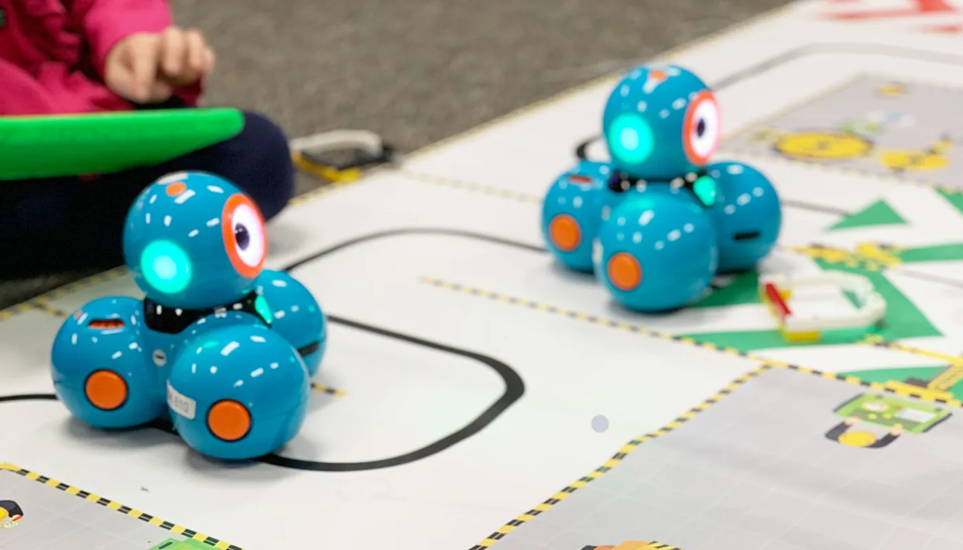 Coding robots moving across an activity mat during a BrainStorm class.