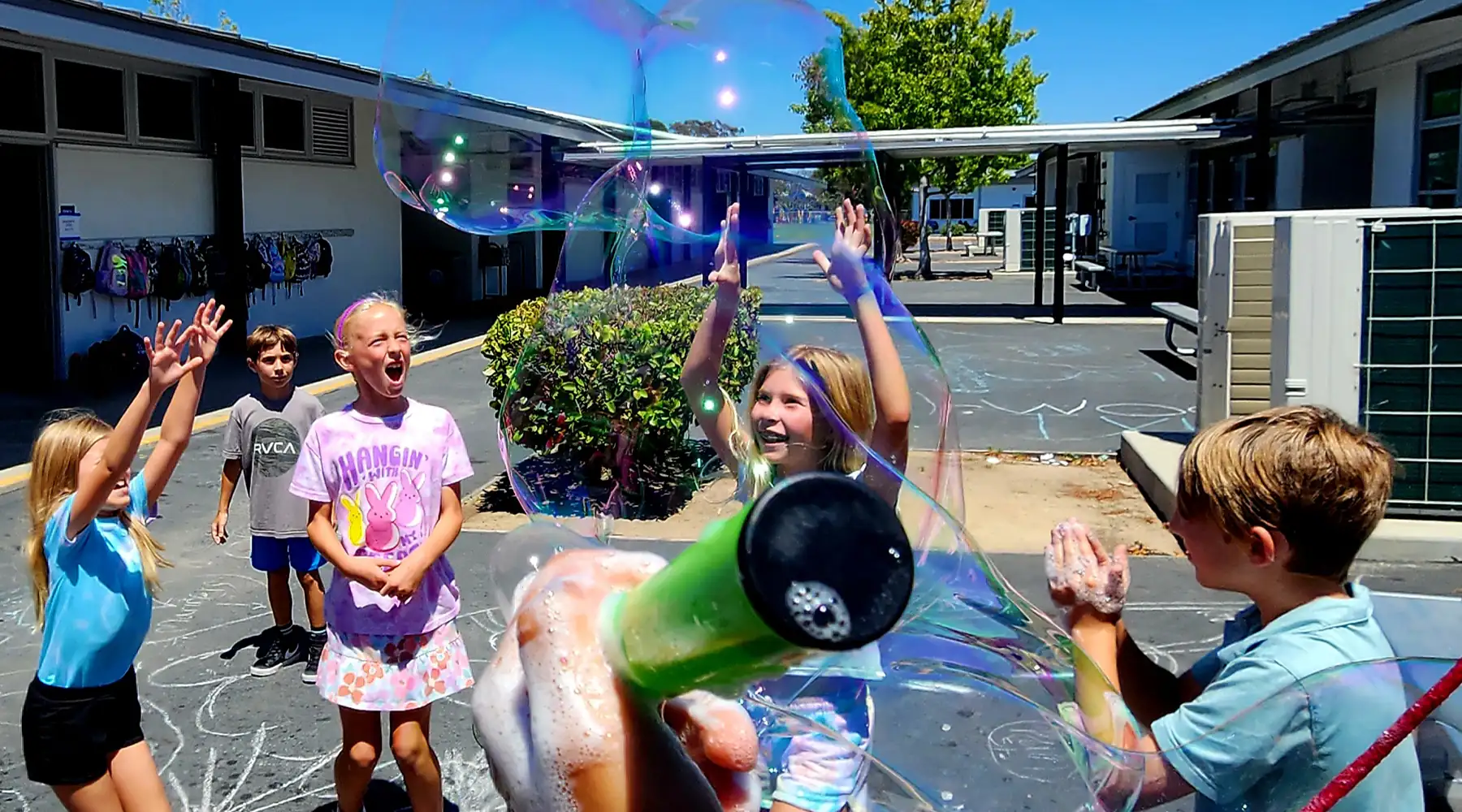 Students creating a giant bubble during an outdoor BrainStorm science activity.