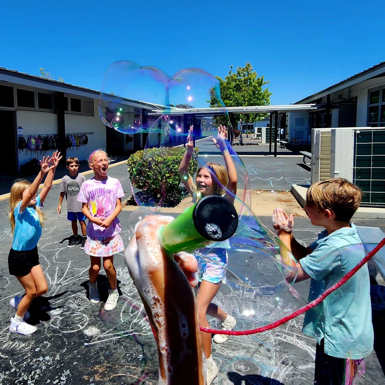 Students making a giant bubble during an outdoor science activity.