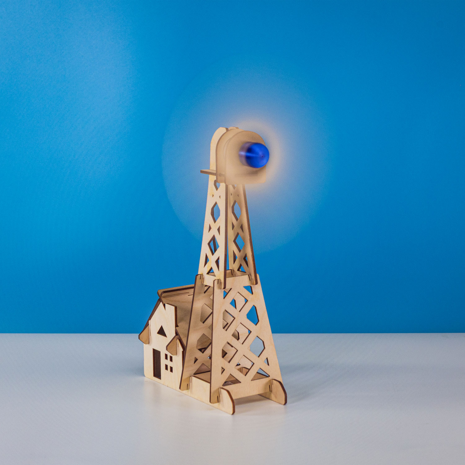 A completed wooden wind turbine spinning against a bright blue background.