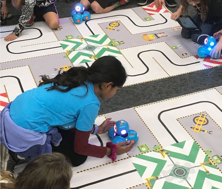 Students plan and test robot routes together on a BrainStorm robotic activity mat.